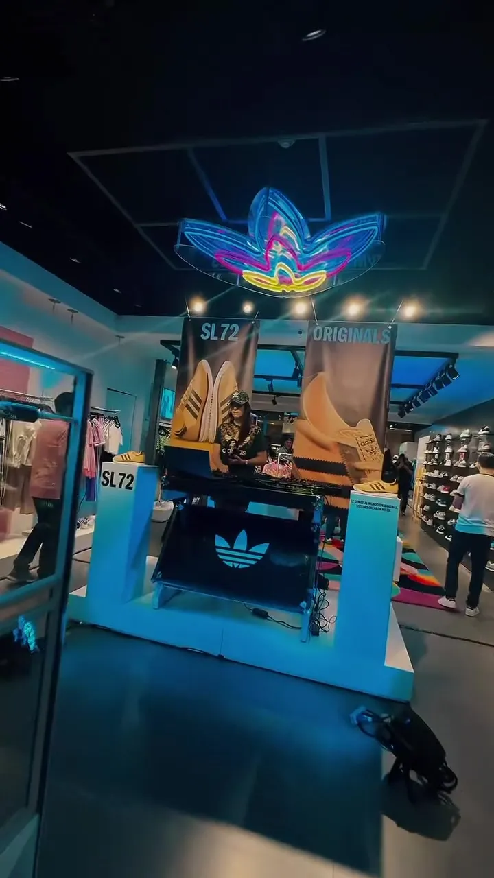 Interior de la tienda Adidas Originals en Santa Cruz con el trébol en neón